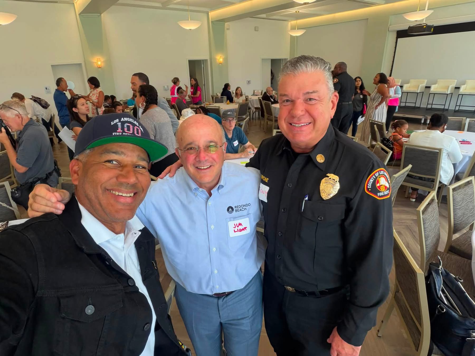 Ray Jackson posing with two men at an indoor event, one wearing a badge cap.