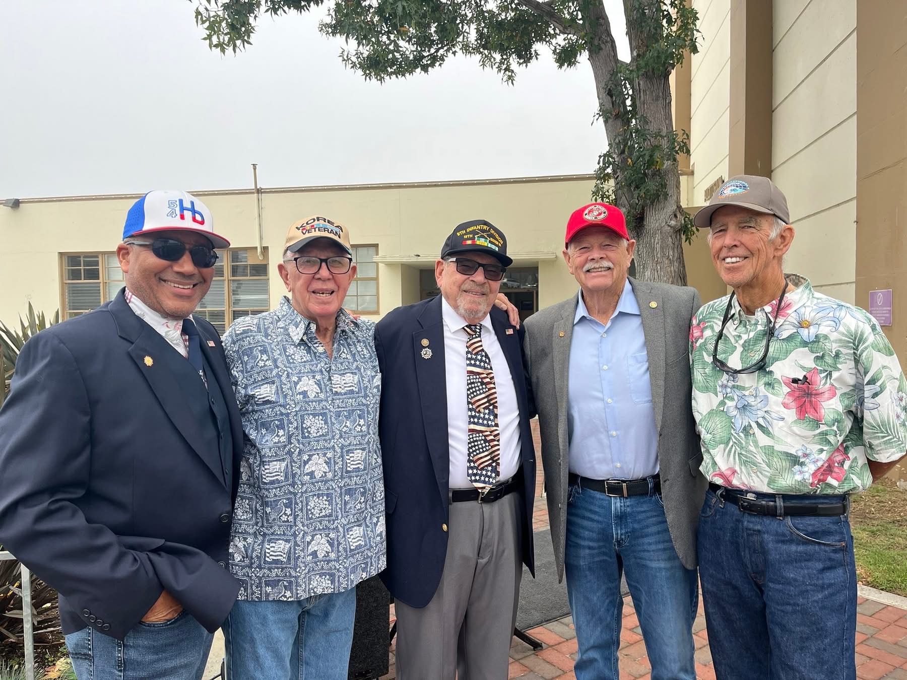 Ray Jackson posing with four men at an outdoor community festival.